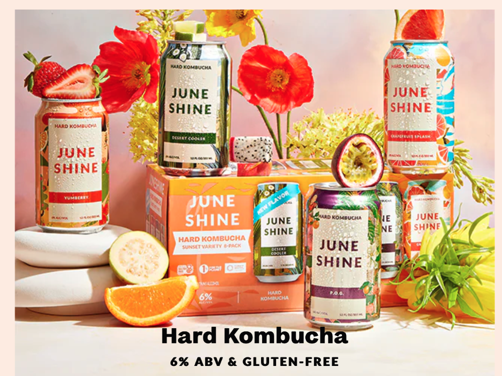 JuneShine selection of drinks positioned among flowers and fresh fruit. 