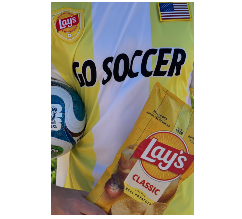 Man holds crisp package in yellow soccer shirt. 
