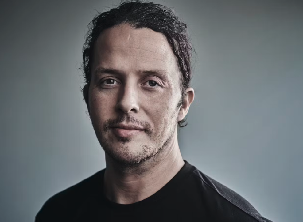 Arnar Halldorsson looks into camera against grey background. 