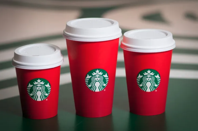 A set of three of Starbucks' controversial red holiday cup on a green table
