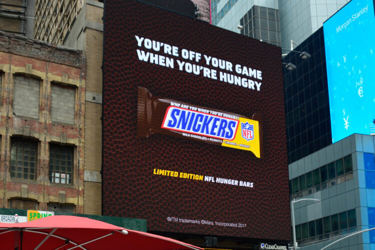Photo of a Snickers ad across a building that is football themed